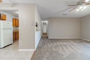 Maumelle apartment for rent - the living room and kitchen of an apartment with a refrigerator and a ceiling fan