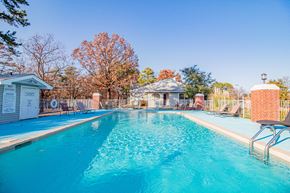 Maumelle apartment for rent - a swimming pool with a house and trees in the background