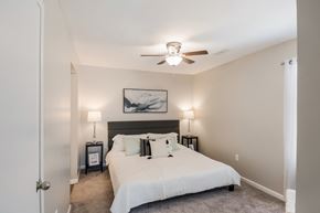Gulfport apartment for rent - A bedroom with a bed, two lamps, and a painting on the wall.