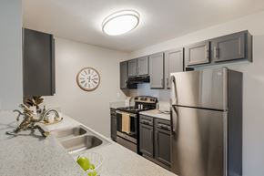 Gulfport apartment for rent - A kitchen with a stainless steel refrigerator, microwave, oven, and sink.