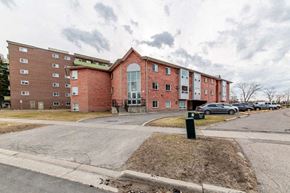 Oshawa apartment for rent - a large brick building with cars parked in front of it