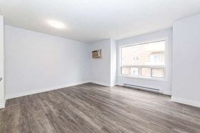 Oshawa apartment for rent - an empty living room with a large window and white walls