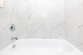 Oshawa apartment for rent - a white bath tub in a white tiled bathroom