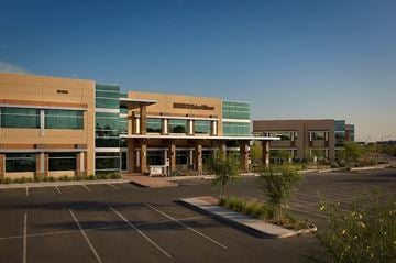 Peoria apartment for rent - A parking lot in front of a multi-story building with a sign that reads "Sunset".