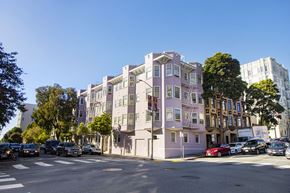 San Francisco apartment for rent - A street view of a row of buildings with cars parked on the side.