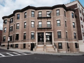 Brighton apartment for rent - A large brick building with a black door and windows.