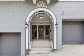 San Francisco apartment for rent - The entrance to a building with a grey facade and a large arched doorway.