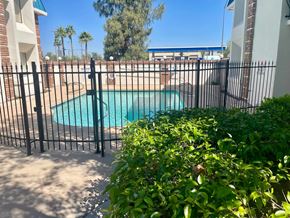 Mesa apartment for rent - a wrought iron fence around a swimming pool in front of a house