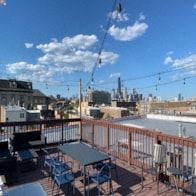 Chicago apartment for rent - a rooftop deck with tables and chairs and a city in the background