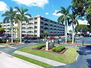 Fort Myers apartment for rent - a building with palm trees in front of a parking lot