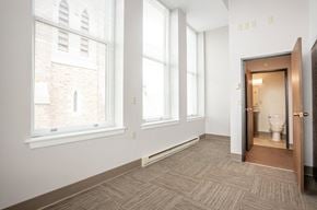 Utica apartment for rent - a bedroom with three large windows and a bathroom with a toilet