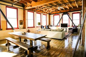 Oakland apartment for rent - A wooden table and benches are in a room with a high ceiling and large windows.