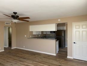 Bakersfield apartment for rent - an empty living room with a kitchen and a ceiling fan