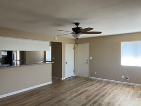 Bakersfield apartment for rent - an empty living room with a ceiling fan and a kitchen