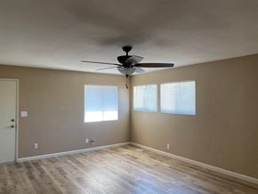 Bakersfield apartment for rent - an empty living room with a ceiling fan and windows