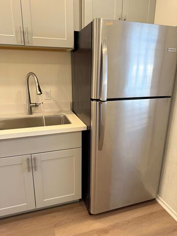Mesa apartment for rent - A stainless steel refrigerator stands in a kitchen with white cabinets.