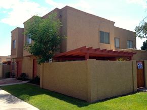 Mesa apartment for rent - A tan house with a red awning and a tree in front.