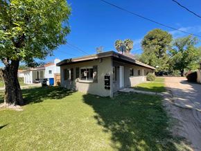 Mesa apartment for rent - A house with a brown roof and a white wall is surrounded by a green lawn.