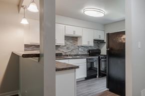Pittsburgh townhouse for rent - a kitchen with white cabinets and a black refrigerator