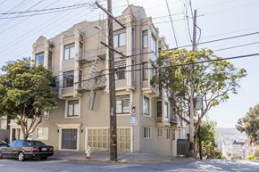 San Francisco apartment for rent - A black car is parked on the street in front of a tan building with a no parking sign.