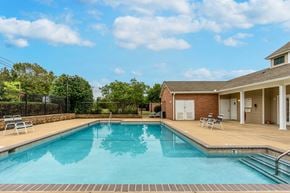 Shelbyville apartment for rent - A swimming pool with a brick building and a fence in the background.