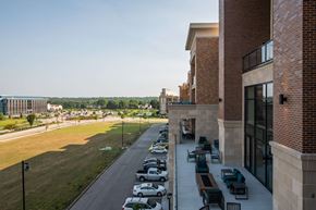 Overland Park apartment for rent - view of the outside of a brick building with cars parked out front and outdoor lounge seating at The Apex at CityPlace, Overland Park, Kansas