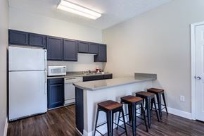 Jackson apartment for rent - A kitchen with a white refrigerator, black cabinets, and a white countertop with three bar stools.