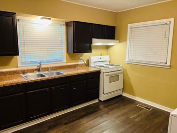 Jonesboro house for rent - A kitchen with black cabinets and a white stove top oven.