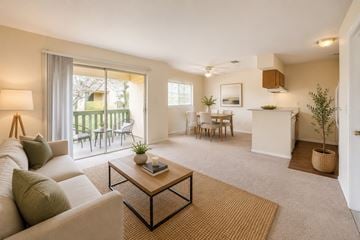 Tarpon Springs apartment for rent - A living room with a white couch, a coffee table, and a dining area with chairs and a table.