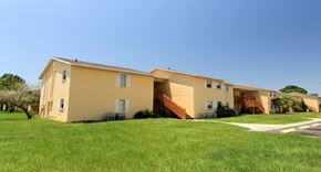 Tarpon Springs apartment for rent - A yellow house with a brown staircase leading to the entrance.