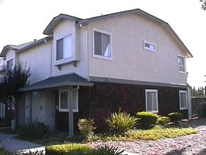 Gilroy apartment for rent - a white and brown house with a sidewalk in front of it