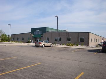 Fargo apartment for rent - a large brick building with a parking lot and a car