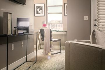 Omaha apartment for rent - A living room with a grey couch and a chair with a grey blanket draped over it.