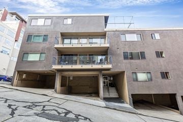 San Francisco apartment for rent - A concrete building with a balcony and stairs leading to the entrance.