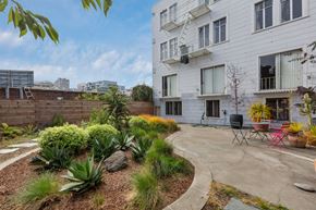 San Francisco apartment for rent - A white building with a balcony and a patio with chairs and plants.