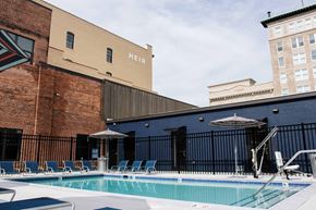Roanoke apartment for rent - a pool with chairs and umbrellas next to a brick building
