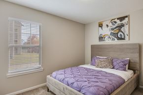 Sherwood apartment for rent - A bedroom with a bed covered in a purple comforter.