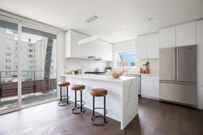 West Hollywood apartment for rent - A kitchen with white cabinets and a marble island.
