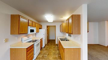 Moorhead townhouse for rent - a kitchen with white appliances and wooden cabinets