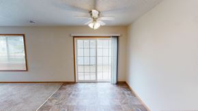 Moorhead townhouse for rent - an empty living room with a sliding glass door and a ceiling fan