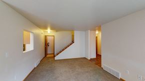 Moorhead townhouse for rent - the living room and dining room of an apartment with carpeted floors and white walls