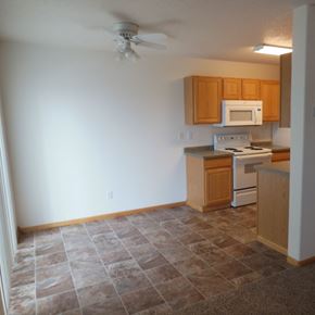 West Fargo townhouse for rent - an empty kitchen with a ceiling fan and wooden cabinets