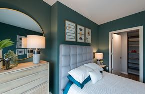 Washington apartment for rent - A bedroom with a white bed and a white dresser with a plant on top.