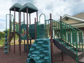 Clover apartment for rent - A playground with a green slide and a green roofed structure.