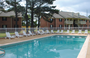 Prattville apartment for rent - A pool with chairs around it and a building in the background.