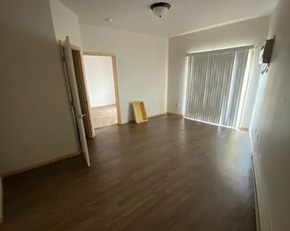 West Fargo apartment for rent - A room with wooden floors and white walls, with a window covered by vertical blinds.