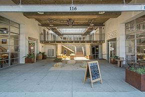 Santa Barbara apartment for rent - The image shows a spacious lobby with a staircase, a signboard, and a few potted plants.