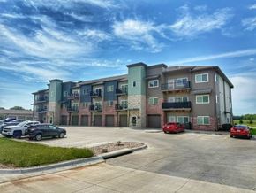 Hickman apartment for rent - A parking lot in front of a multi-story apartment building with cars parked.