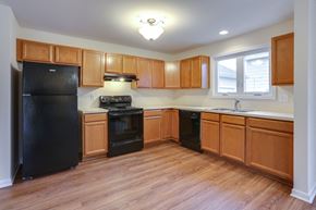 Amherst triplex for rent - an empty kitchen with wood flooring and black appliances