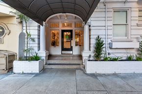San Francisco apartment for rent - A white building with a black door and a green sign above it.